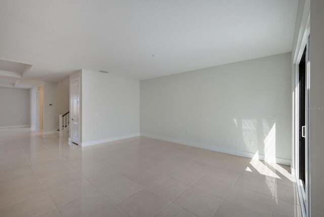 spare room with baseboards, stairs, visible vents, and light tile patterned floors
