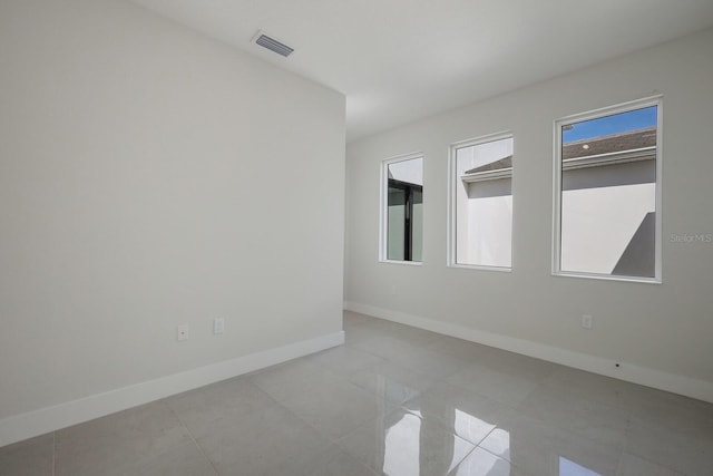 tiled empty room with baseboards and visible vents