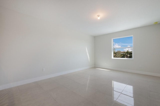 unfurnished room with light tile patterned floors and baseboards