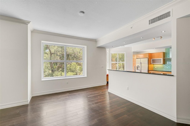 empty room with a textured ceiling, crown molding, and dark wood-type flooring