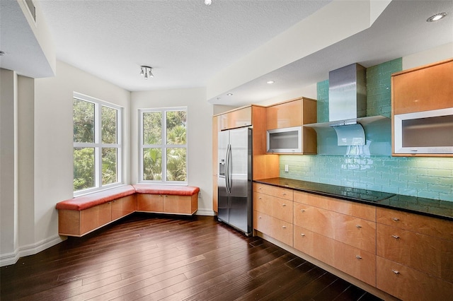 kitchen with wall chimney range hood, tasteful backsplash, black electric stovetop, stainless steel refrigerator with ice dispenser, and dark hardwood / wood-style flooring