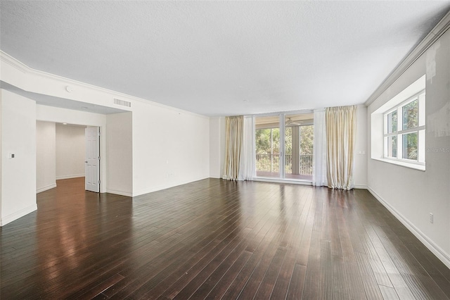 empty room featuring ornamental molding, a textured ceiling, and dark wood-type flooring