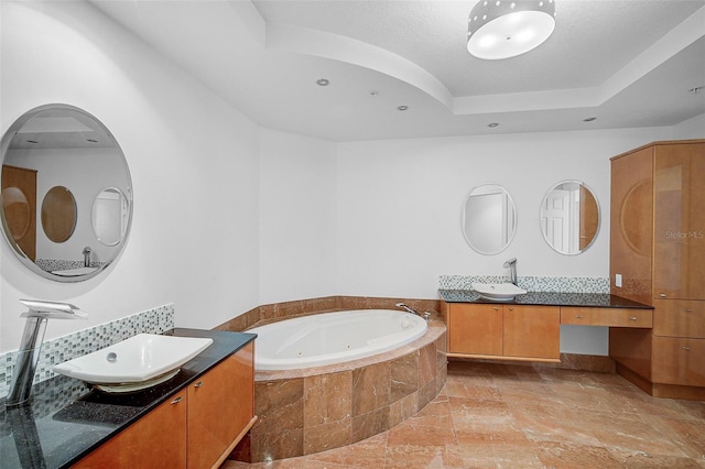 bathroom featuring tiled tub, a raised ceiling, tile floors, and vanity