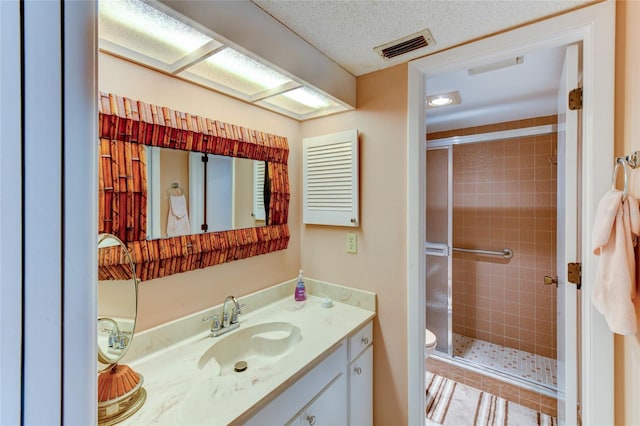 bathroom featuring a shower with door, vanity, a textured ceiling, and toilet