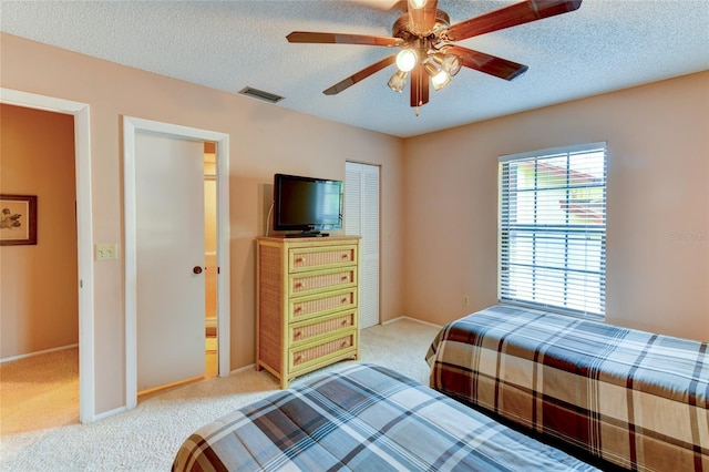 carpeted bedroom featuring ceiling fan and a textured ceiling