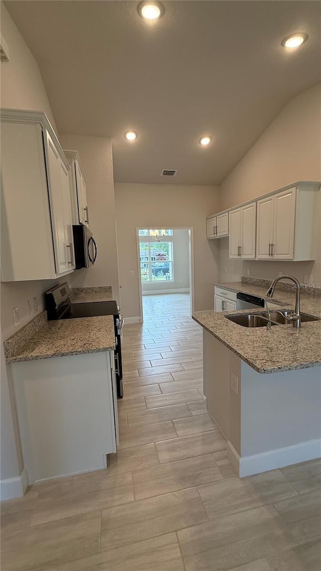 kitchen featuring vaulted ceiling, sink, white cabinets, light stone counters, and stainless steel appliances