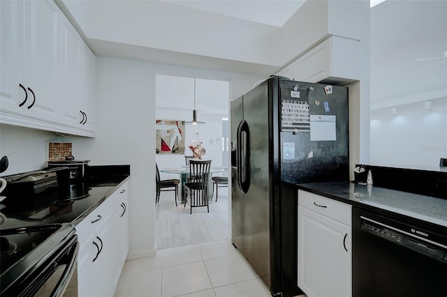 kitchen with dark stone counters, white cabinetry, black appliances, and light tile flooring