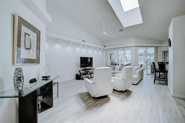 living room with vaulted ceiling with skylight, ceiling fan, light wood-type flooring, and track lighting