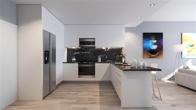 kitchen featuring white cabinets, stainless steel appliances, light wood-type flooring, and kitchen peninsula