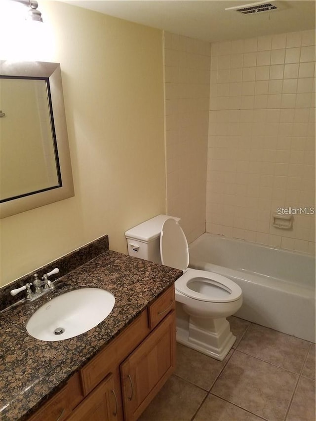 full bathroom featuring tiled shower / bath combo, tile floors, vanity with extensive cabinet space, and toilet