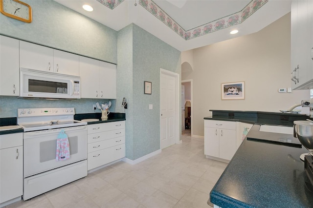 kitchen with white cabinets, light tile flooring, white appliances, and a towering ceiling