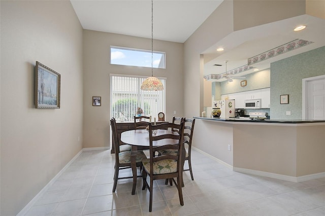 dining area with light tile floors and a towering ceiling