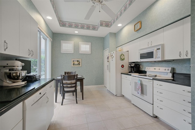 kitchen featuring light tile flooring, ceiling fan, white appliances, white cabinets, and a raised ceiling