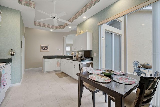 kitchen with light tile flooring, white cabinets, ceiling fan, and ornate columns