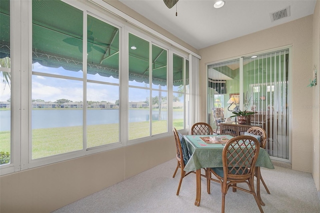 sunroom / solarium with ceiling fan and a water view