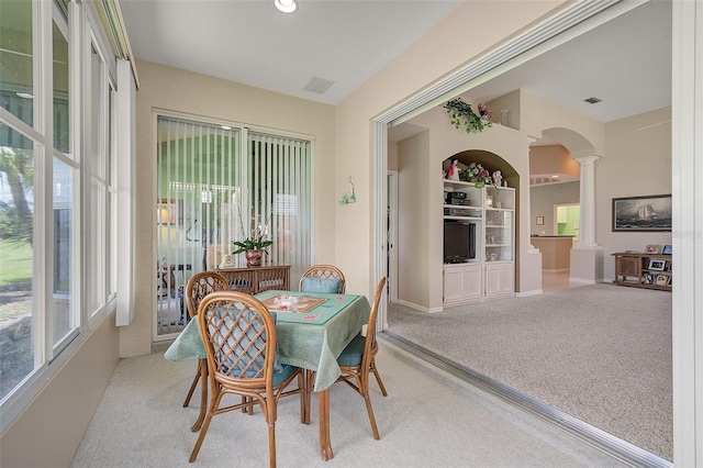 dining room featuring decorative columns, light colored carpet, and built in shelves