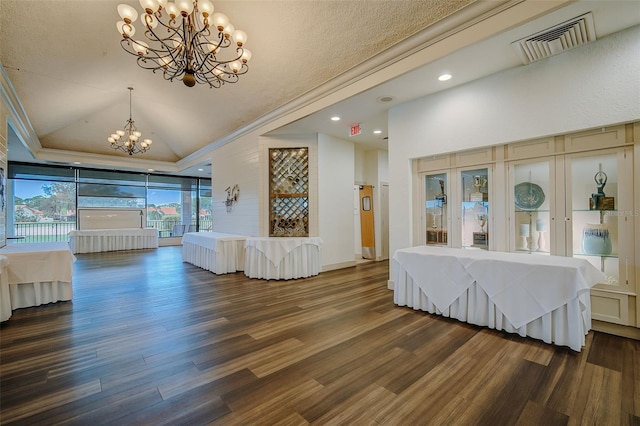 unfurnished living room featuring ornamental molding, a raised ceiling, dark hardwood / wood-style flooring, and an inviting chandelier