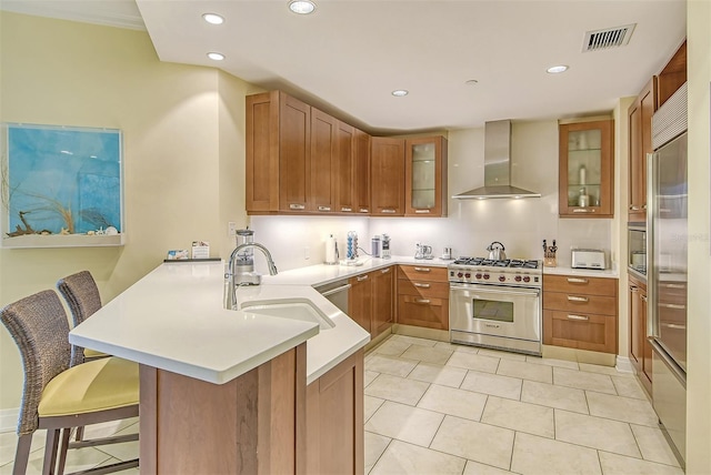 kitchen with a kitchen bar, kitchen peninsula, designer range, and wall chimney exhaust hood