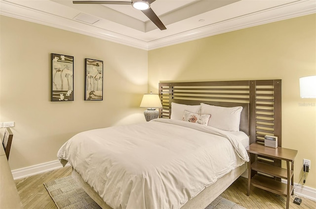 bedroom featuring a tray ceiling, ceiling fan, light hardwood / wood-style flooring, and crown molding