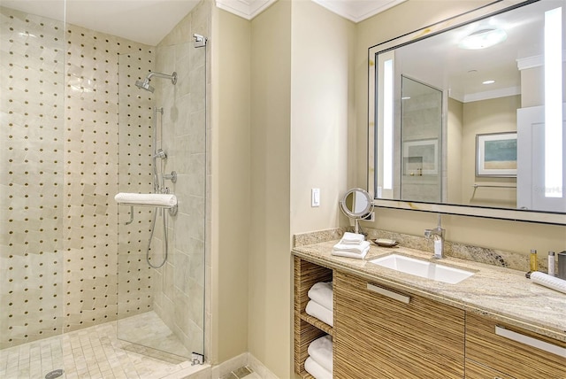 bathroom featuring crown molding, tiled shower, and vanity with extensive cabinet space