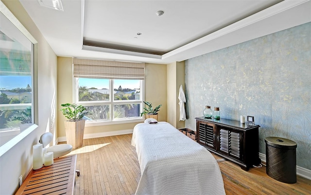 bedroom with a tray ceiling and light wood-type flooring