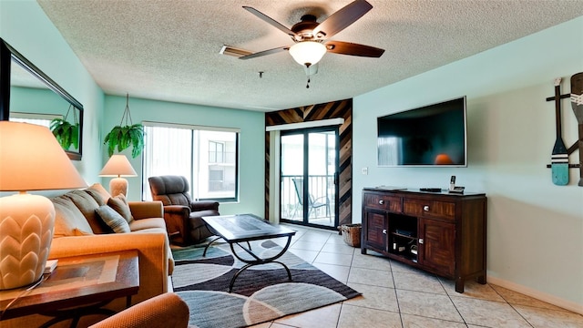 living room featuring light tile floors, ceiling fan, and a textured ceiling