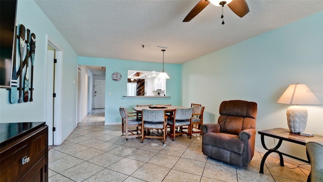 tiled dining space with a textured ceiling and ceiling fan