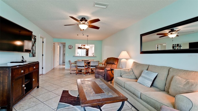 living room featuring a textured ceiling, ceiling fan with notable chandelier, and light tile floors