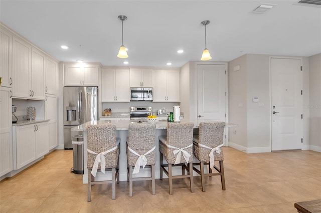 kitchen with light stone countertops, a center island, hanging light fixtures, stainless steel appliances, and a kitchen breakfast bar