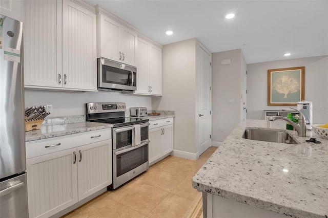 kitchen featuring white cabinets, sink, light stone countertops, and stainless steel appliances