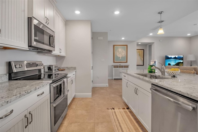 kitchen featuring light stone counters, stainless steel appliances, sink, pendant lighting, and white cabinets