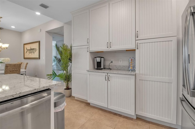 kitchen featuring light stone countertops, white cabinetry, stainless steel appliances, and light tile patterned floors