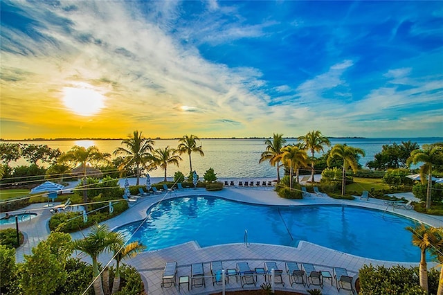 pool at dusk featuring a water view