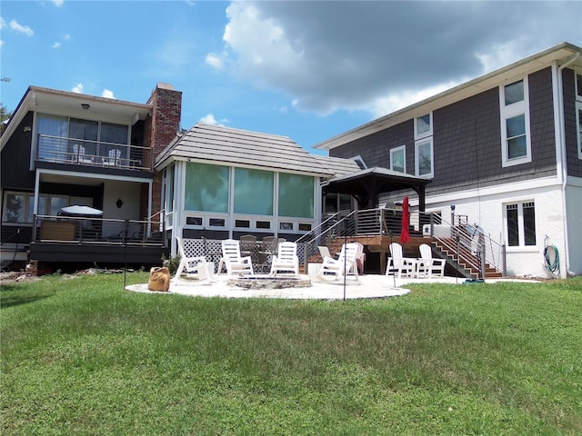 rear view of house with a yard, a sunroom, a balcony, and a patio area