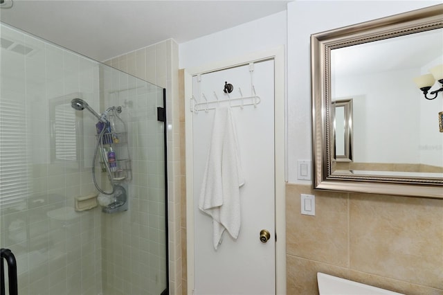 bathroom with tile walls and a shower with shower door