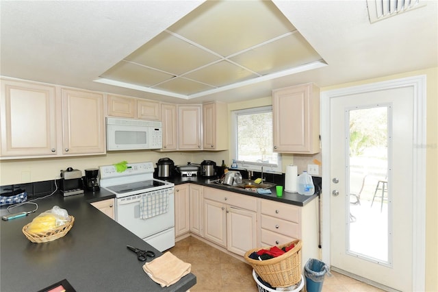 kitchen with white appliances, a tray ceiling, sink, and light tile patterned floors