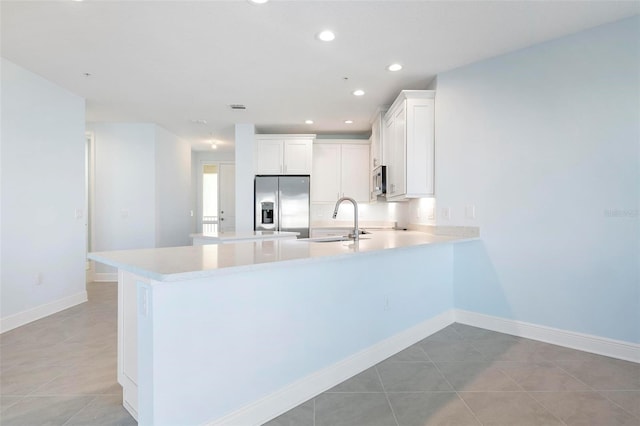 kitchen featuring kitchen peninsula, appliances with stainless steel finishes, white cabinetry, and sink