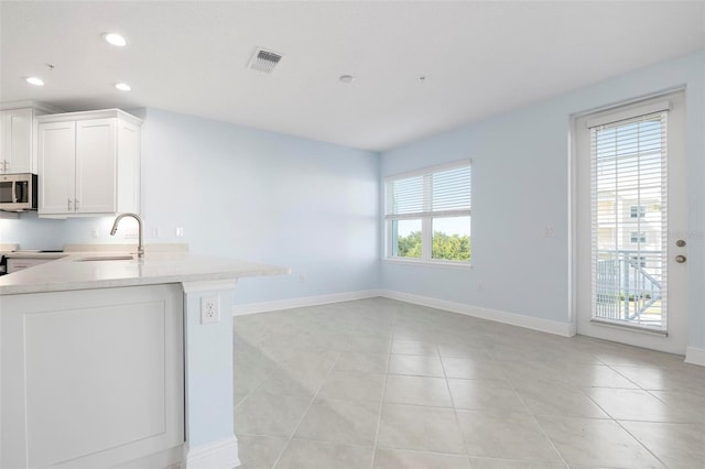 kitchen with white cabinets, light stone counters, and a wealth of natural light