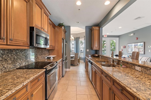 kitchen featuring backsplash, stainless steel appliances, light stone counters, and sink