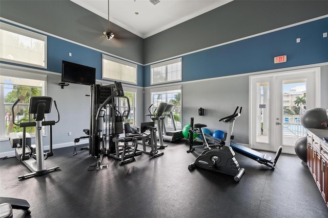 gym featuring ceiling fan, ornamental molding, and a high ceiling