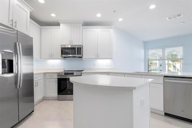 kitchen featuring appliances with stainless steel finishes, sink, light tile patterned floors, a center island, and white cabinetry