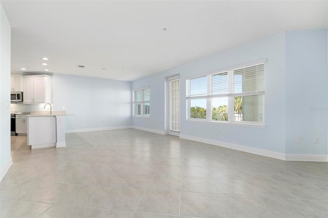 unfurnished living room with light tile patterned flooring and sink