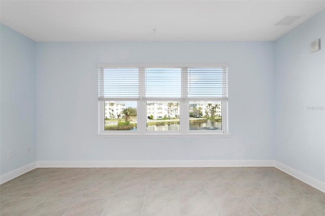 unfurnished room with a water view, a wealth of natural light, and light tile patterned flooring