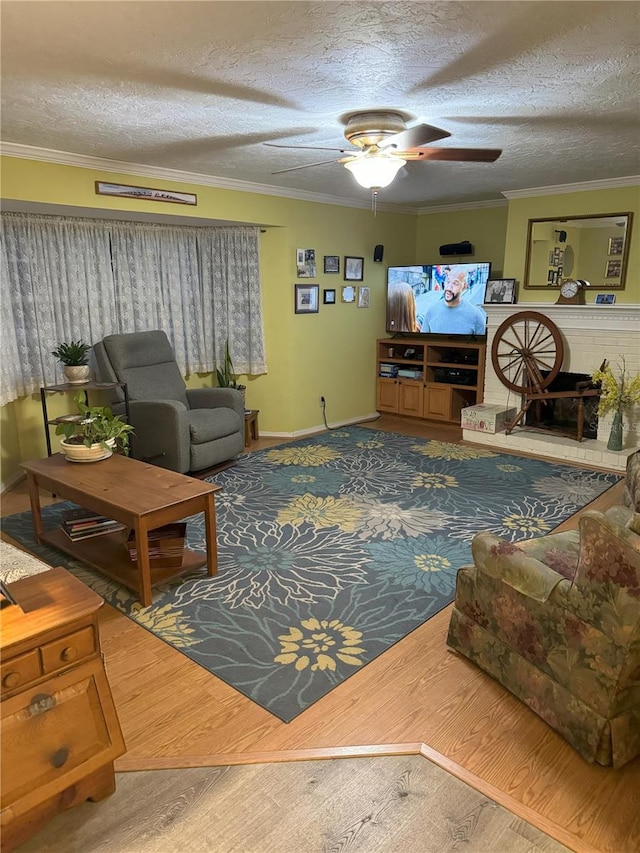 living room featuring crown molding, a brick fireplace, hardwood / wood-style flooring, ceiling fan, and a textured ceiling