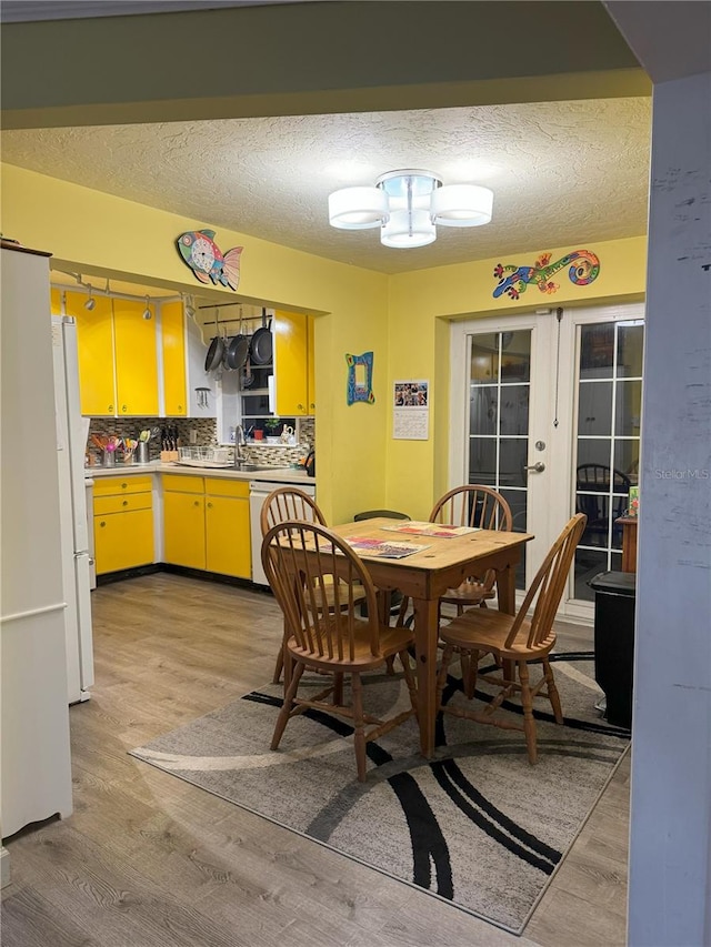 kitchen featuring dishwasher, light wood-type flooring, backsplash, and french doors