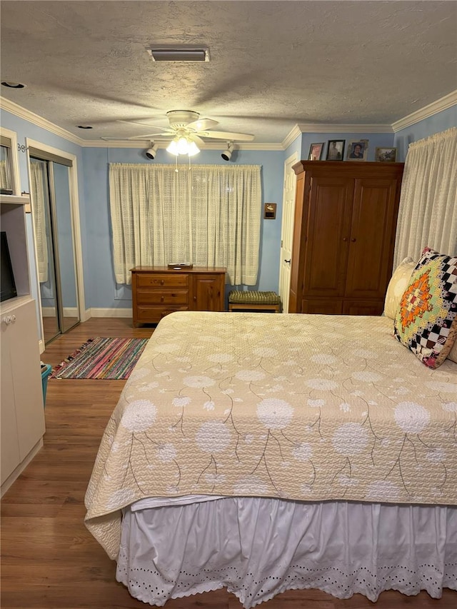 bedroom featuring hardwood / wood-style flooring, ceiling fan, ornamental molding, and a textured ceiling