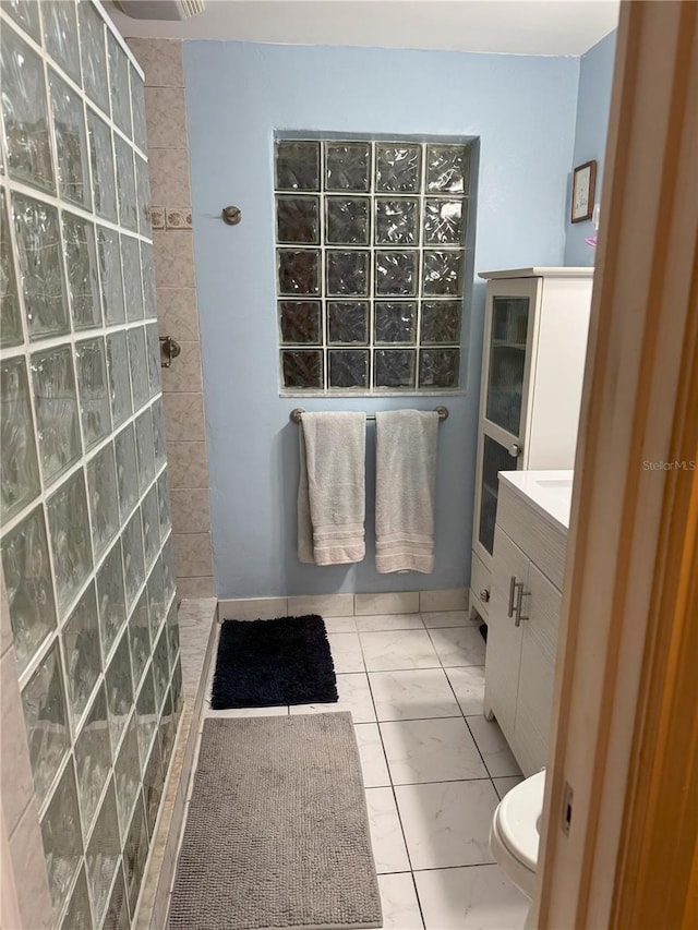 bathroom with a tile shower and vanity