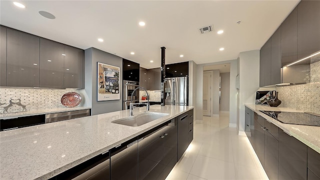 kitchen featuring stainless steel fridge, sink, light tile floors, backsplash, and light stone countertops