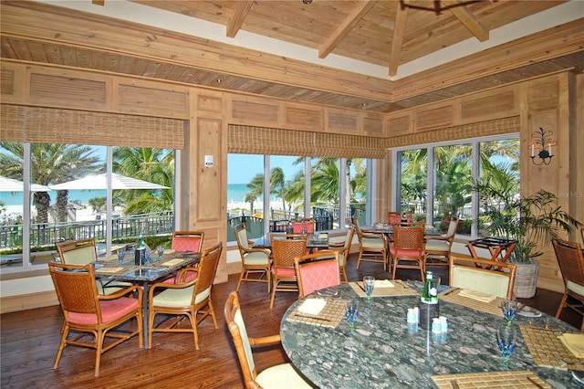 dining area with dark hardwood / wood-style floors, wooden walls, beamed ceiling, wooden ceiling, and a water view