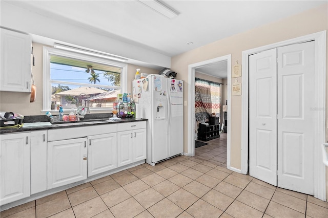 kitchen featuring light tile patterned flooring, white cabinets, sink, and white fridge with ice dispenser